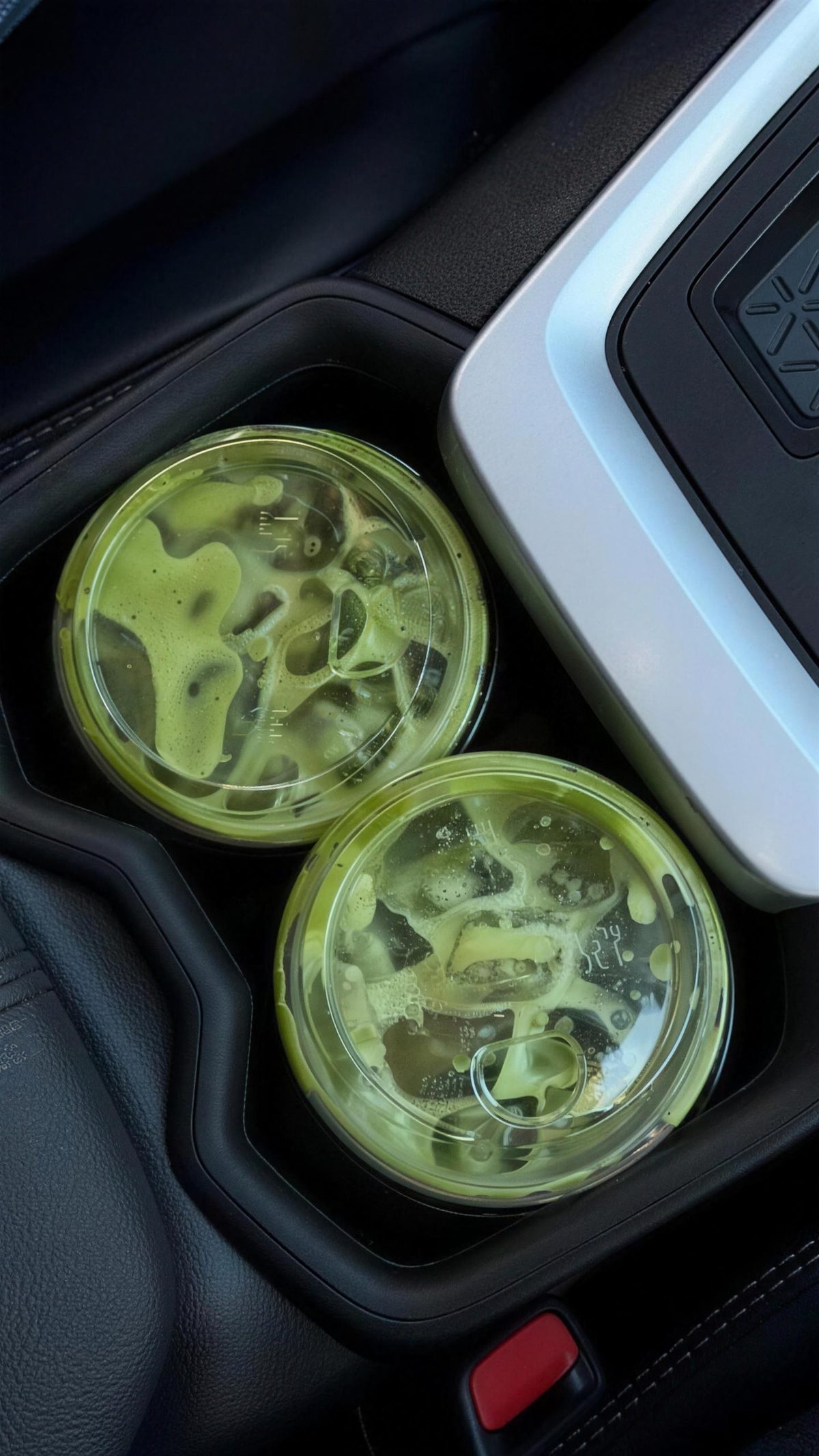 Two iced matchas in a car cupholder